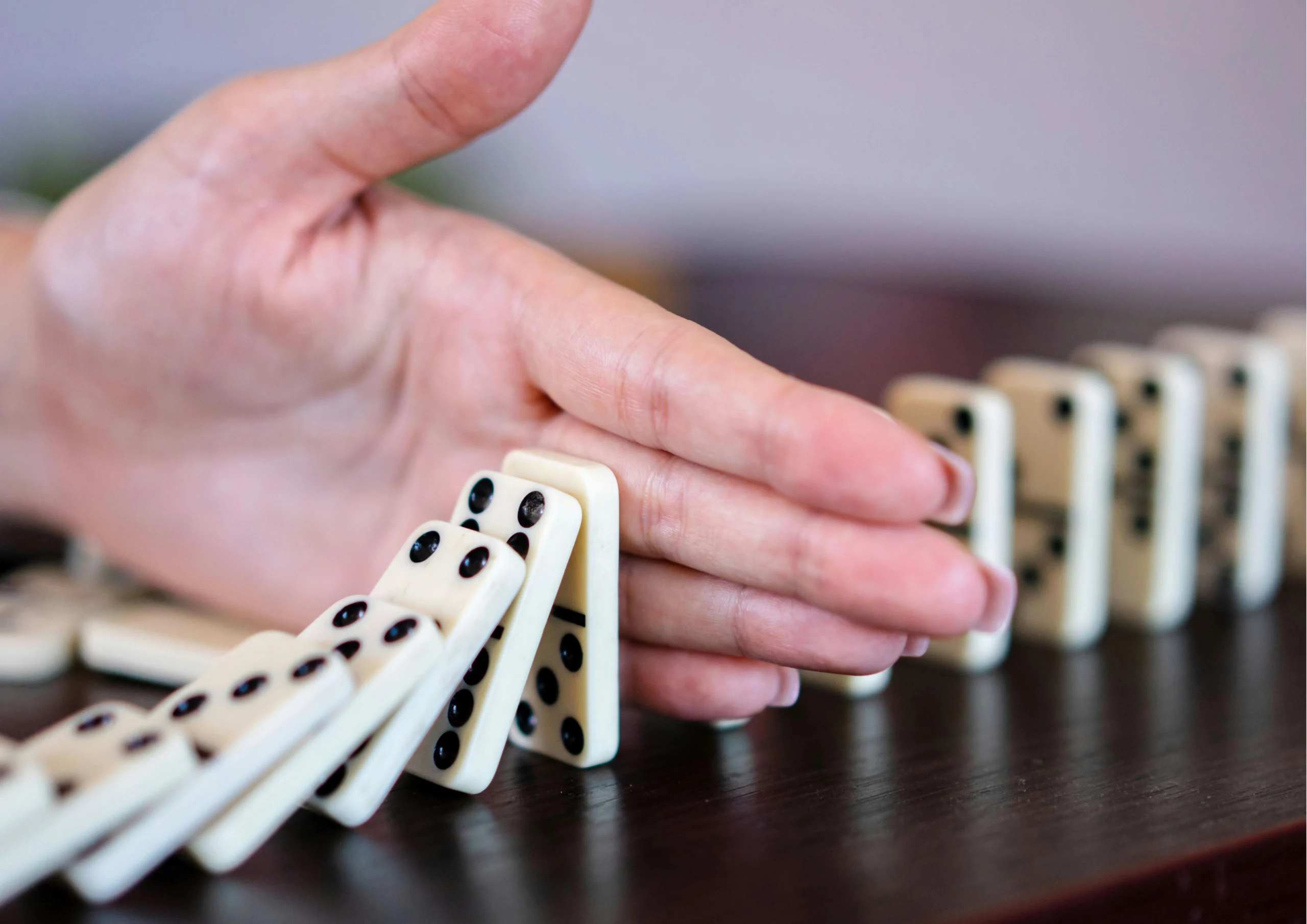 Main arrêtant une série de dominos en train de tomber, symbolisant la reprise de contrôle dans un processus de décision.