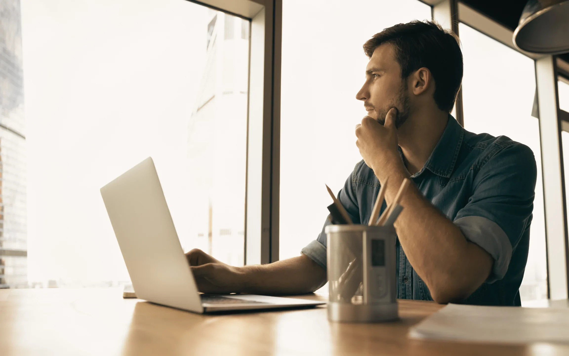 Homme en réflexion devant son bureau lors d’un questionnement sur sa trajectoire professionnelle.