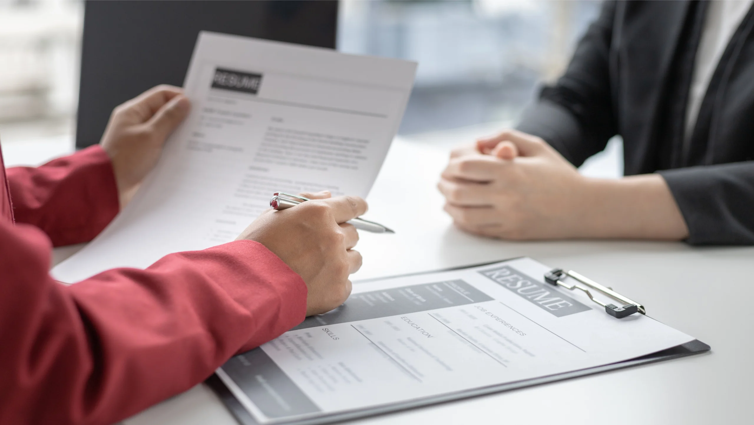 Deux personnes échangent autour de documents professionnels, l’une tenant une feuille, l’autre consultant un CV dans un contexte d’orientation ou de bilan de compétences.