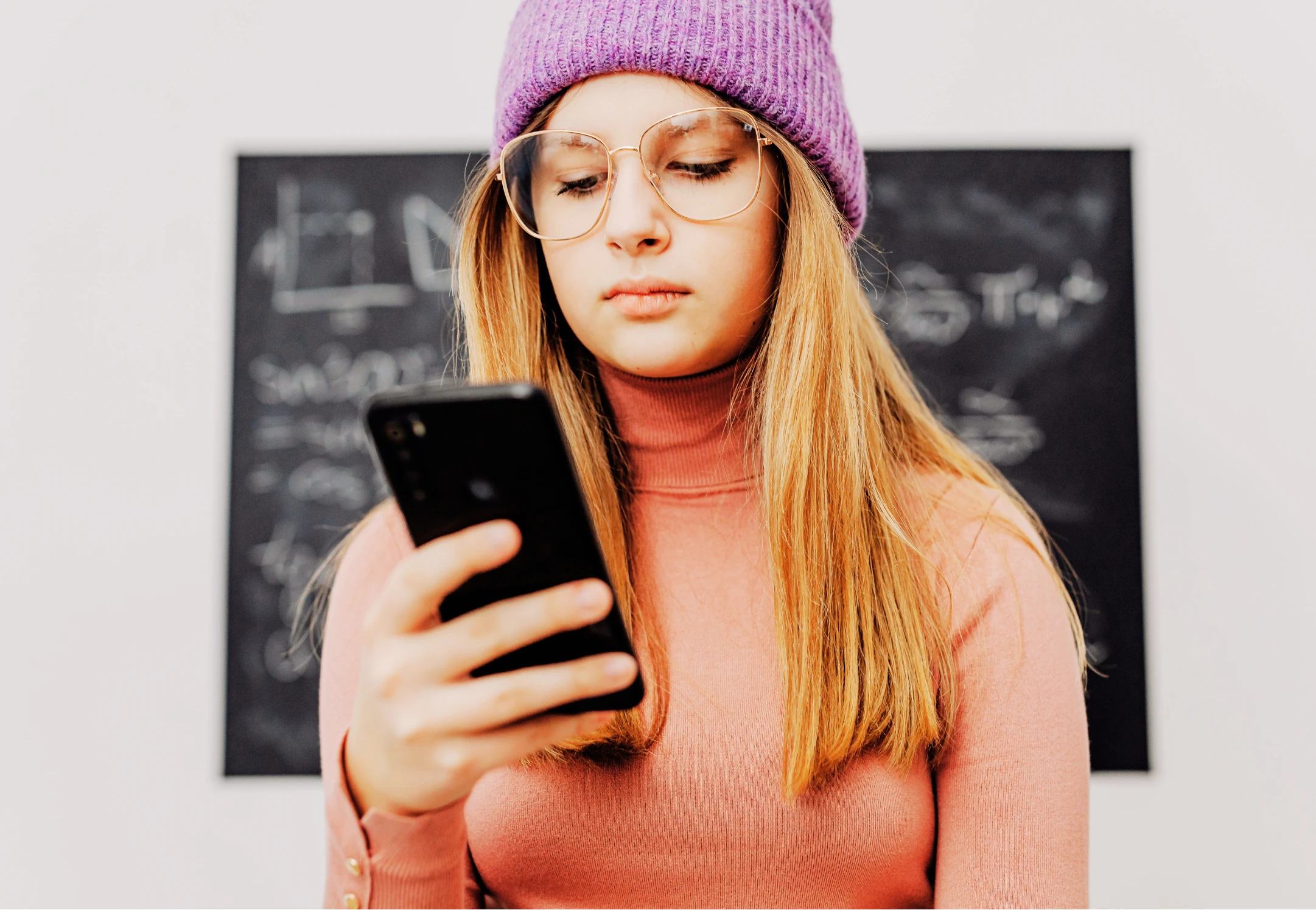 Jeune fille consultant son téléphone, pensive